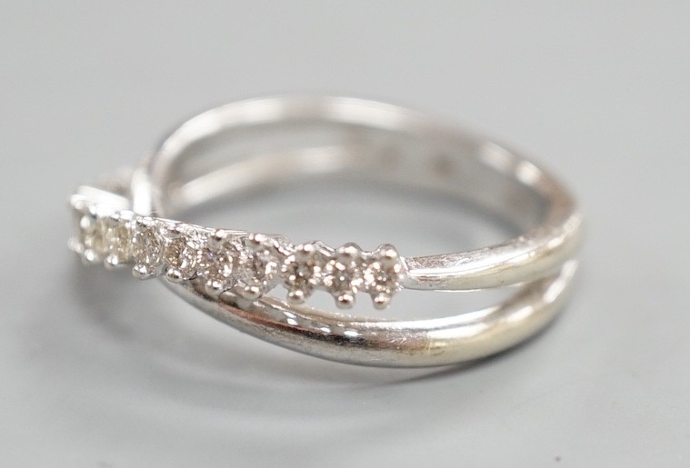 A modern 18ct white gold and diamond chip set half hoop crossover ring, size O, gross weight 3.9 grams.